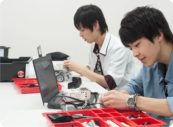 教材を用いてロボットを組み立て作業をする学生