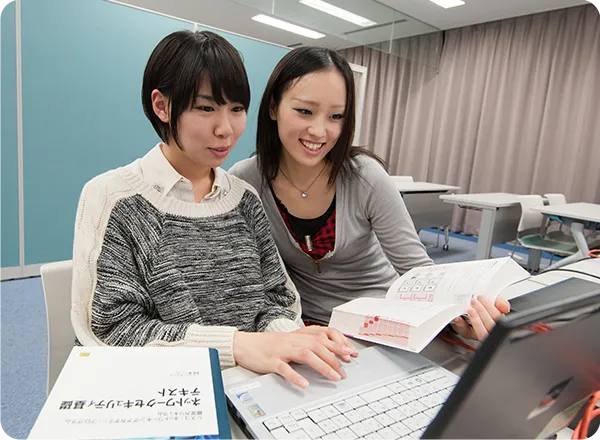 教本とパソコンを眺めて学習する２名の学生の様子