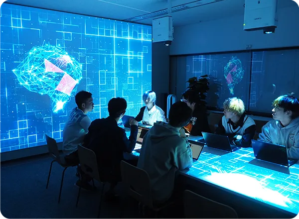 AI実践センターの青いライト中で講義を行う学生達の様子