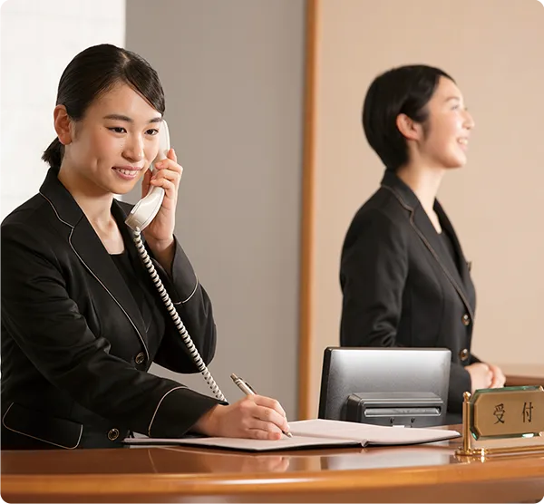 電話をしながらメモを取るホテルの受付の様子