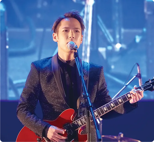 学生がギターを持ちステージで歌っている様子