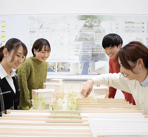 卓上の模型図に複数人で議論する学生の様子