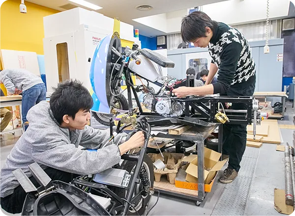 車両フレームの組み立て作業を行う学生