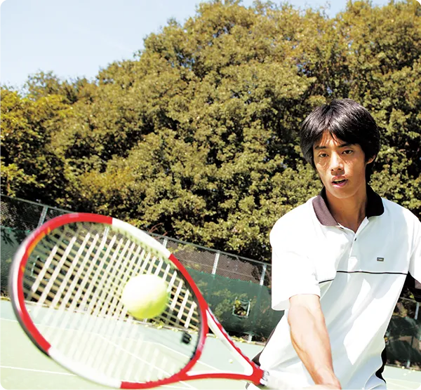 テニスのボールを打つ学生