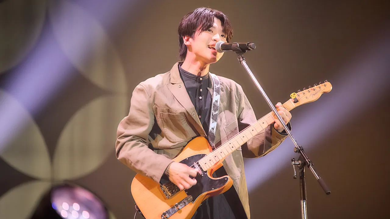 学生が照明に照らされたステージでライブパフォーマンスをする様子