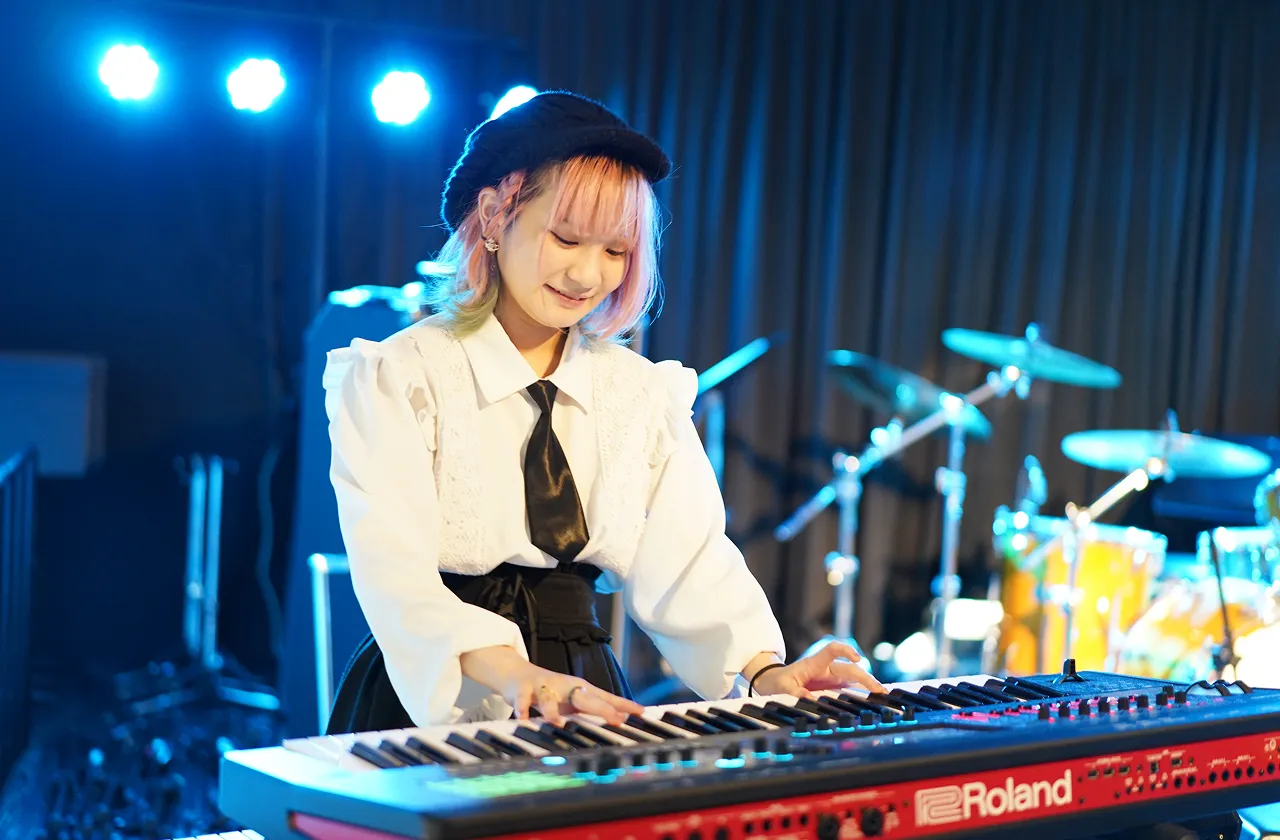 学生が照明に照らされたステージでライブパフォーマンスをする様子