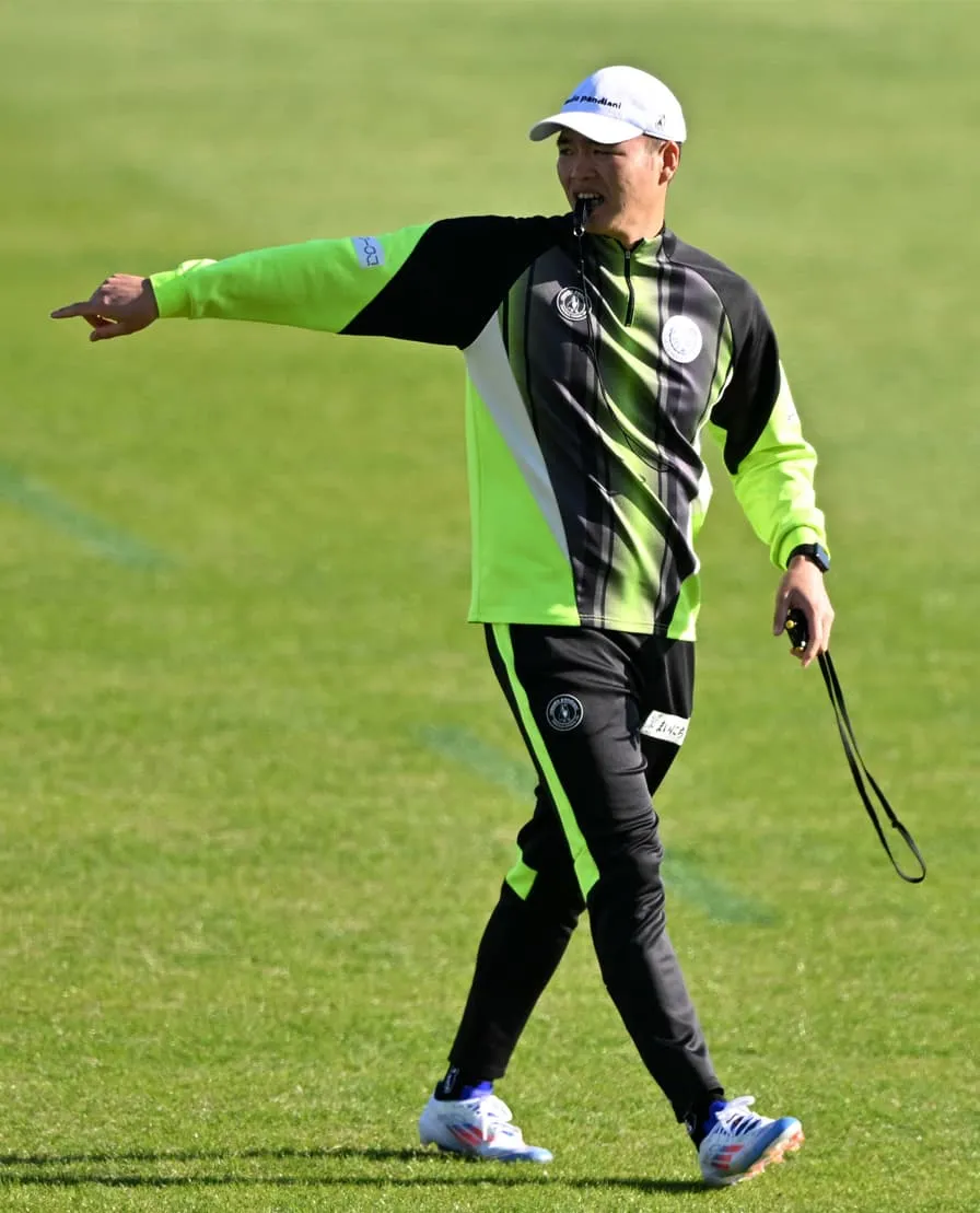 フィールドをジャージ姿で歩きながらストップウォッチを片手に、ホイッスルを加えてなんらかの指示をだしている中村さん