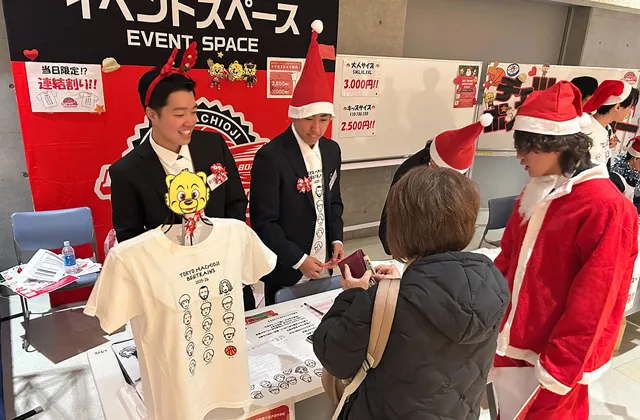 スポーツビジネスコースの学生が、サンタクロースの衣装でTシャツ販売を行なっている様子