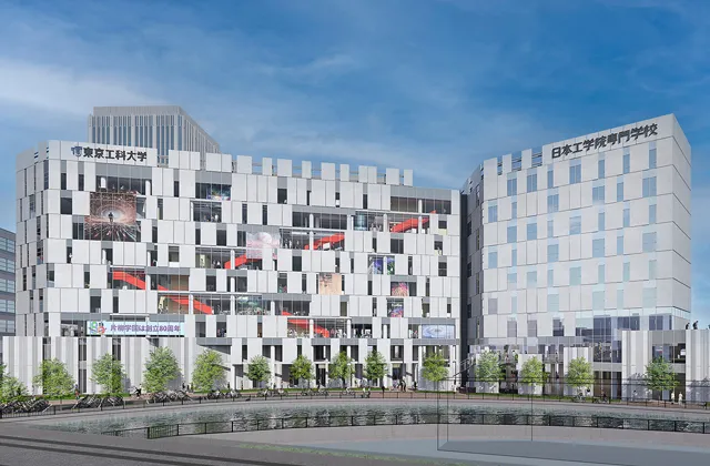 白色を基調とし、窓から赤色の階段が見えるビル