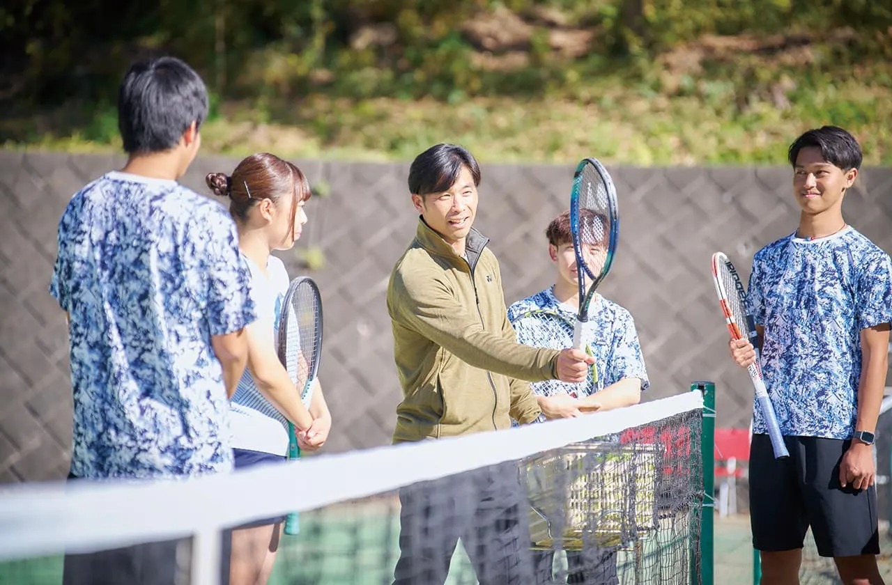 コートで指導を受けながらコーチと談笑する様子