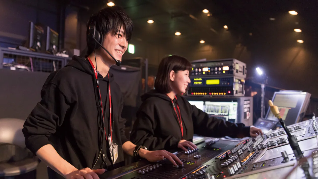 ライブ会場でミキサーを操作する学生コンサートスタッフ2人