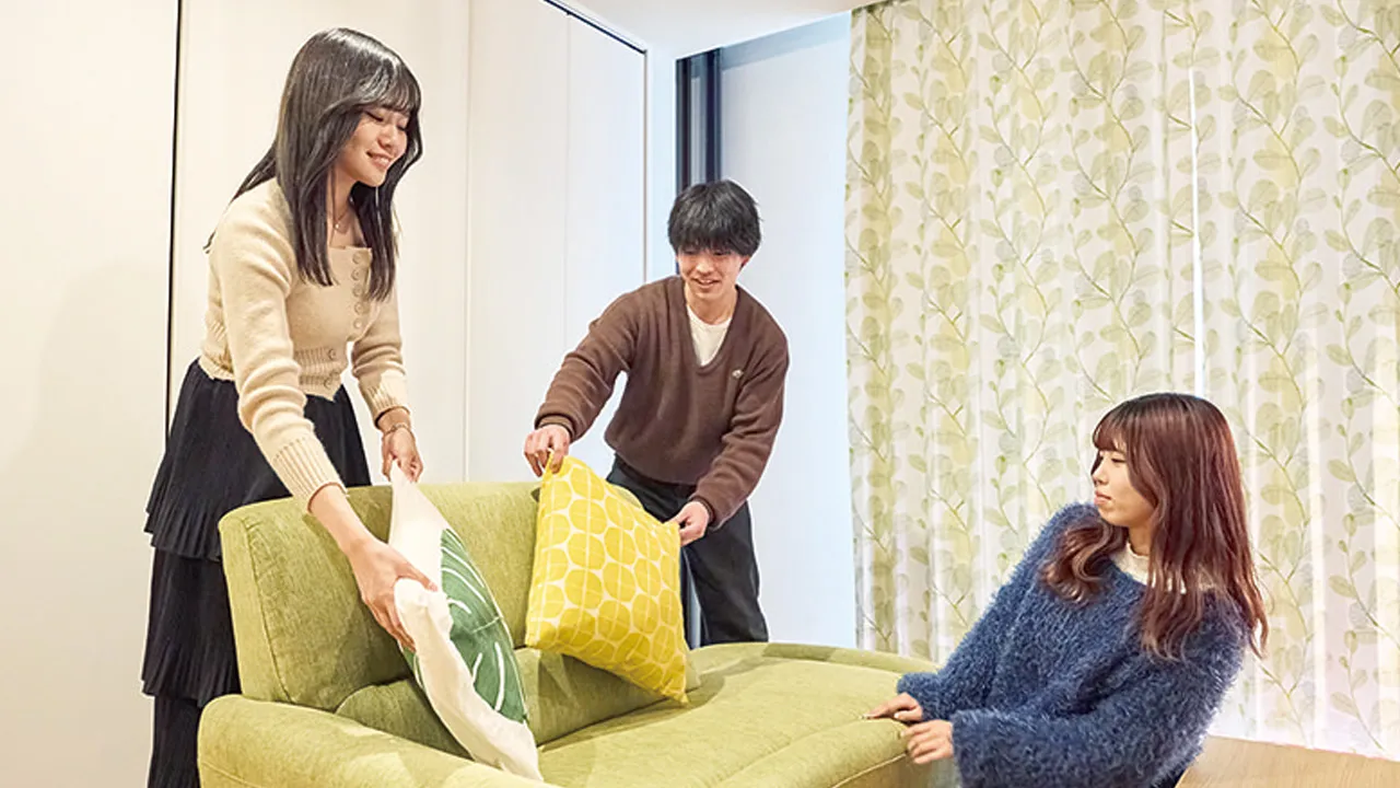 ソファーとクッションを使ってインテリアコーディネートをする3人の学生
