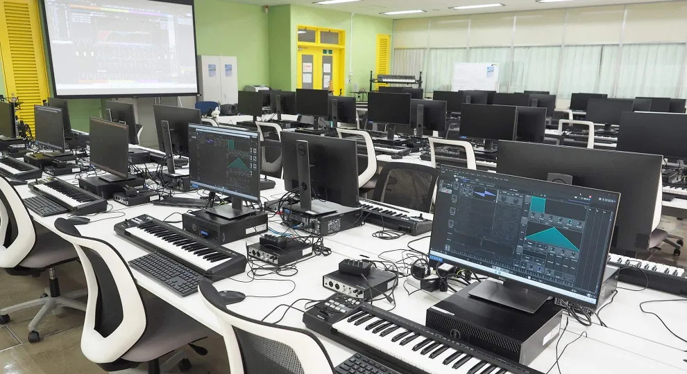 パソコン、キーボード、ヘッドホンなどの機材が完備された音楽実習室