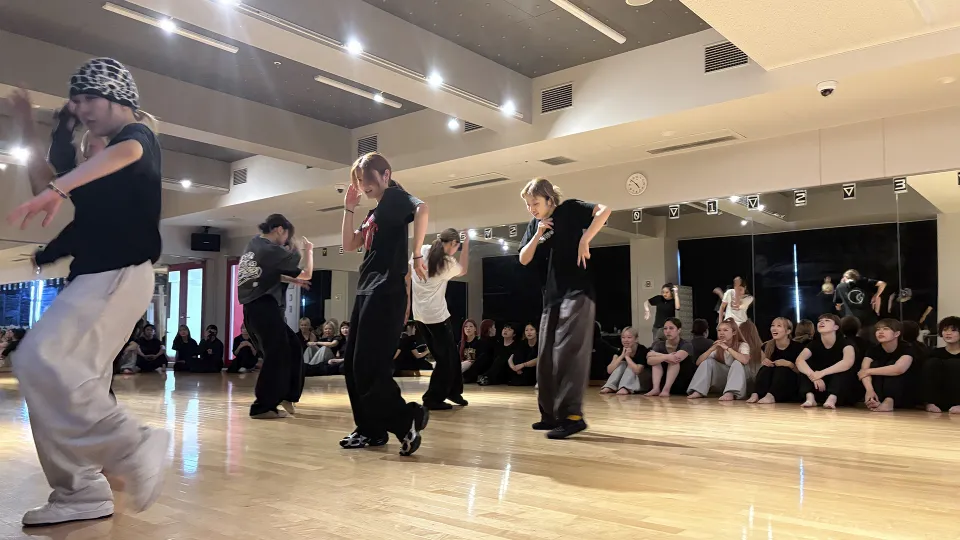 ダンススタジオで踊る学生グループとその周りで見守る学生たち